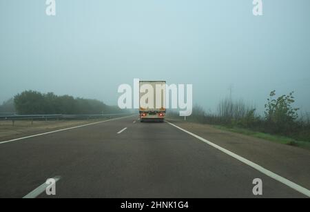 Fahren hinter einem LKW unter dichtem Nebel. Fahrkonzept bei schlechtem Wetter Stockfoto