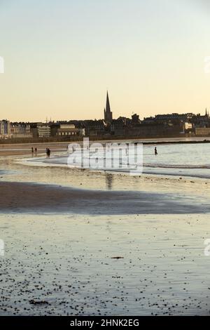 Romantischer Spaziergang von Menschen vor Sonnenuntergang am malerischen Strand von Saint Malo. Bretagne, Frankreich Stockfoto