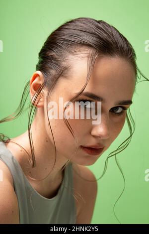 Porträt einer jungen Frau mit gerafften dunklen Haaren mit dicken Lippen isoliert auf grün Stockfoto