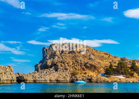 St Pauls Bay Lindos Strand Panoramablick mit türkisfarbenen klaren Wasserbooten Touristen und Sonne auf Rhodos Griechenland. Stockfoto