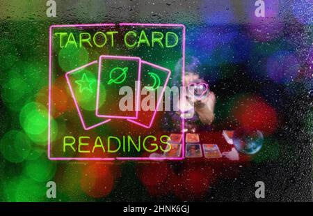 Tarot-Kartenlesungen Neon-Anmeldefenster mit psychischem Tarot-Kartenleser im Hintergrund Stockfoto