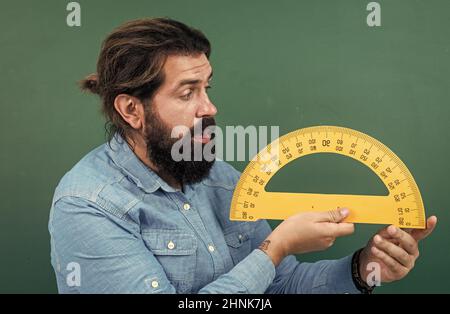 Mann überrascht mit Größe gemessen an Winkelmesser Lineal Mathematik-Werkzeug, Schule Stamm Disziplinen Stockfoto