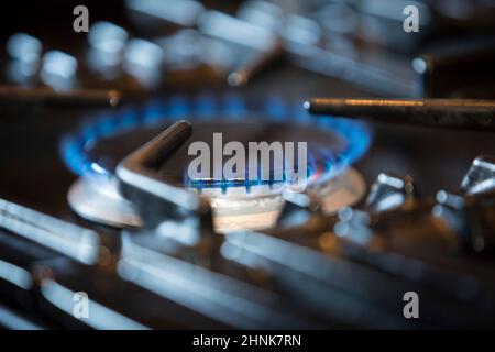 Nahaufnahme eines brennenden Gasrings, der auf dem Kochfeld eines Hausgaskochers in einer britischen Küche leuchtet. Stockfoto