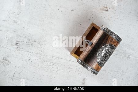 Kleiner hölzerner verzierter leerer Brustdeckel geöffnet, auf weißem Steinbrett, Foto von oben Stockfoto