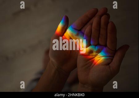 Regenbogenstrahl auf der Hand einer Frau. Stockfoto