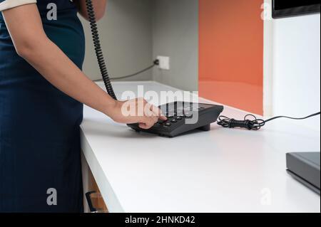 Zimmermädchen in blauer Uniform mit Telefon im Hotelzimmer Stockfoto