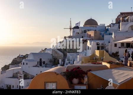 Weiß getünchte Häuser und Windmühlen in Oia in warmen Sonnenstrahlen auf Santorini. Griechenland Stockfoto
