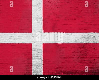 Vollformat-Foto einer verwitterten Flagge Dänemarks auf einer verputzten Ziegelwand. Stockfoto