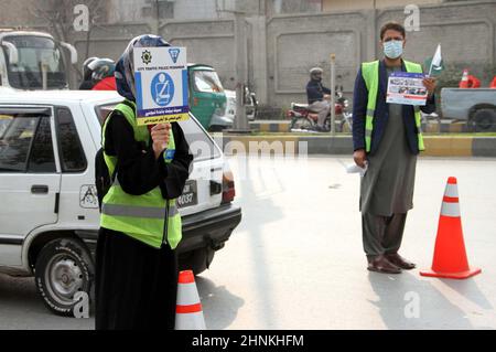 Die Teilnehmer der Freiwilligen-Organisation für den Straßenverkehr halten am Donnerstag, dem 17. Februar 2022, in Peshawar Informationsbroschüre und Horten über die Verkehrssicherheit während der Kampagne für Verkehrsgesetze und Straßenverkehrssicherheit ab. Stockfoto