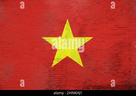 Vollformatfoto einer verwitterten Flagge Vietnams auf einer verputzten Ziegelwand. Stockfoto