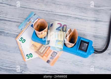 Euro-Banknoten in einer Steckdose, steigende Preise, teurer Ökostrom, Deutschland Stockfoto