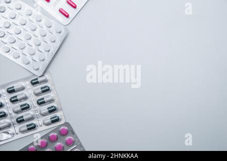 Tabletten und Kapseln in der Packung liegen auf der Seite auf weißem Hintergrund mit einem Platz für Text in der Mitte. Stockfoto