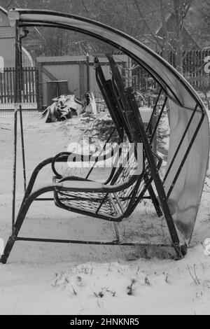 Schaukel in einem verschneiten Garten. Hinterhof eines Landhauses Stockfoto