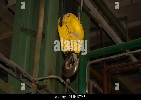 Industrieller gelber Kranhaken, der in der Fabrik hängt Stockfoto