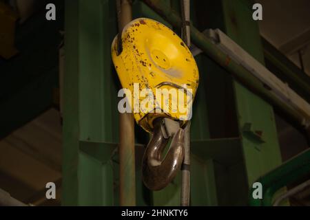 Industrieller gelber Kranhaken, der in der Fabrik hängt Stockfoto