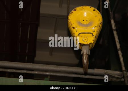 Industrieller gelber Kranhaken, der in der Fabrik hängt Stockfoto