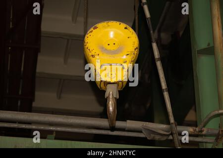 Industrieller gelber Kranhaken, der in der Fabrik hängt Stockfoto