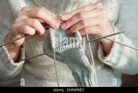 Gemütlich stricken Frau in gestrickten warmen Pullover genießt stricken Arbeit zu Hause in gemütlichen Winterzeit. Nahaufnahme. Stockfoto