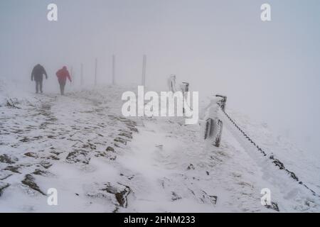 Winterstraße bergauf bei schlechtem Wetter. Reisende klettern die Straße bergauf. Stockfoto