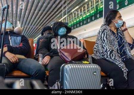 Flughafen Charles de Gaulle, Paris, Frankreich, 01. Januar 2022- Passagiere mit Schutzmasken sitzen und warten in der Abflughalle Stockfoto