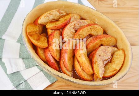 Nahaufnahme des Kuchenblechs mit frisch gemischter Füllung, bevor ein Apfelkuchen gebacken wird Stockfoto