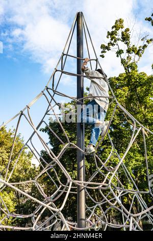 Mädchen klettert auf einem Seilspielplatz im Innenhof der Stadt Stockfoto