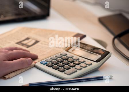 Taschenrechner und Finanzzeitung. Coronavirus Konzept. Heimarbeit Stockfoto