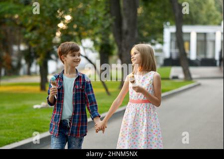 Romantische Kindertage im Sommerpark, Freundschaft, erste Liebe. Junge und Mädchen essen Eis. Kinder haben Spaß im Freien, glückliche Kindheit Stockfoto