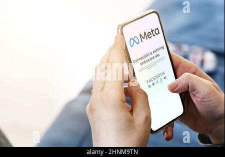Frau, die ein Telefon mit der mobilen Meta-App auf dem Bildschirm hält Stockfoto