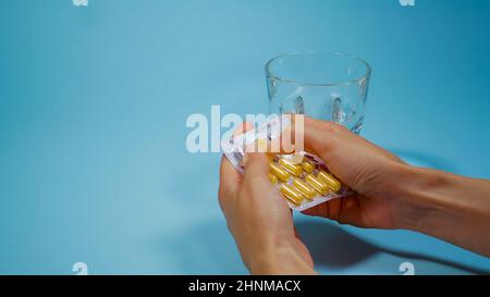 Weibliche Patientin, die Medizin nimmt. Hände mit Pille, Kapsel und Glas Wasser in Blisterpackungen. Konzept der Gesundheitsversorgung und medizinischen Behandlung. Stockfoto