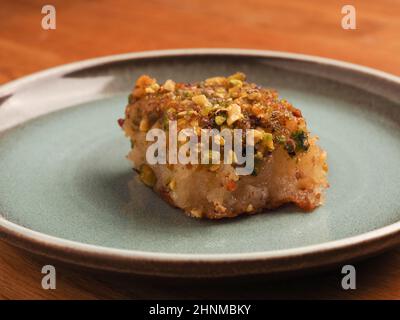 Syrischer Grießkuchen mit Zuckersirup, leckerer Harisse auf blauer Keramikplatte, syrisches Dessert Stockfoto