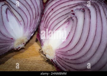 Schnittmengen von rohen roten Zwiebeln. Nahaufnahme über Holzschneidebrett Stockfoto