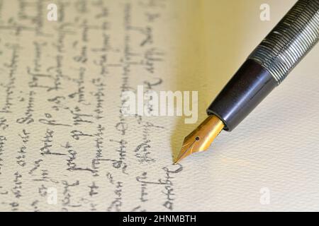 Füllfederhalter auf Papier mit Tintentext auf Vintage-Handschrift. Nahaufnahme. Füllfederhalter auf einem antiken handgeschriebenen Brief Stockfoto