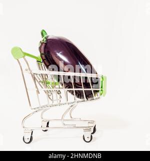 Mini-Metall-Supermarkt-Trolley mit lila reifen Auberginen auf weißem Hintergrund Stockfoto