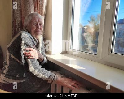 Die ältere Frau mit gasrechnung vor der Heizung kühler. Die Zahlung für die Heizung im Winter. Stockfoto