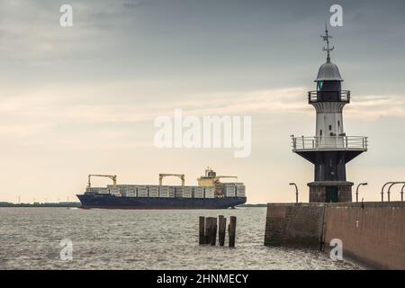 Leuchtturm und Frachtschiff Stockfoto