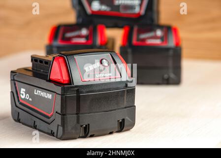 Akku für Akku-Bohrmaschine. Schrauberbatterie. Vier Batterien mit Ladeanzeige liegen auf einem Holzhintergrund Stockfoto