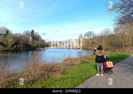 Junge Frau, die an einem sonnigen Wintertag die Aussicht an der Themse in Richtung Richmond fotografiert, im Westen Londons, England Stockfoto