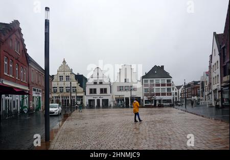 Rheine, NRW, Deutschland - 16 2022. Februar Ein Platz namens Marktplatz an einem regnerischen Tag. Die drei weißen Häuser in der Ferne sind Denkmäler. Stockfoto