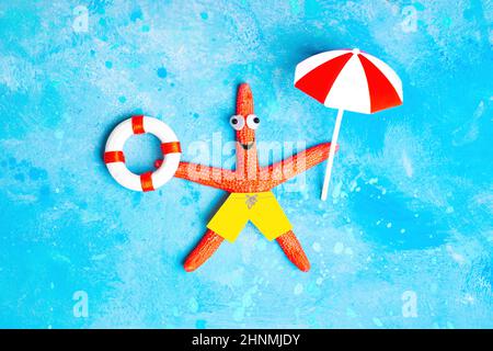 Lustige rote Seesterne Charakter hält eine Rettungsboje und ein Sonnenschirm liegt auf einem hellblauen Hintergrund imitiert Wasser. Kreatives Konzept für einen Urlaub am Meer. Stockfoto