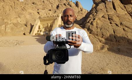 Ägypten, Sharm El Sheikh - 30. März 2020. Ein erwachsener schwarzer ägyptischer Videofilmer mit einem Sony Camcorder in den Händen tötet Touristen vor dem Hintergrund der Wüste in Sharm El Sheikh. Stockfoto