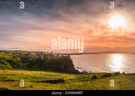 Dramatischer Sonnenuntergang in mittelalterlichen Ruinen Dunluce Castle auf der Klippe, Bushmills, Nordirland Drehort der beliebten TV-Show Game of Thrones Stockfoto