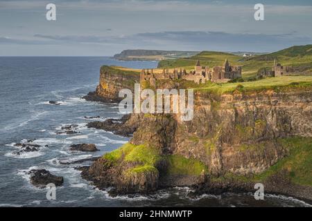 Dunluce Castle das von Sonnenlicht beleuchtete, am Rande der Klippen gelegene Bushmills Northern Ireland. Drehort der beliebten TV-Show Game of Thrones Stockfoto