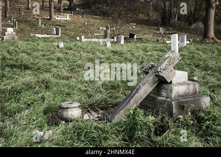 Verlassene bewachsene Friedhöfe mit grauen Steingrabsteinen Stockfoto