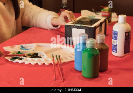 Junges Mädchen, das eine Holzkiste mit Aquarellen malt Stockfoto