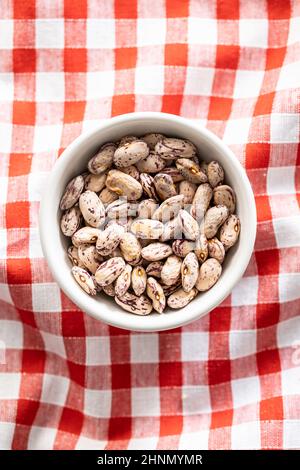 Cranberry-Bohnen. Borlotti-Bohnen in einer Schüssel auf karierter Tischdecke. Draufsicht. Stockfoto