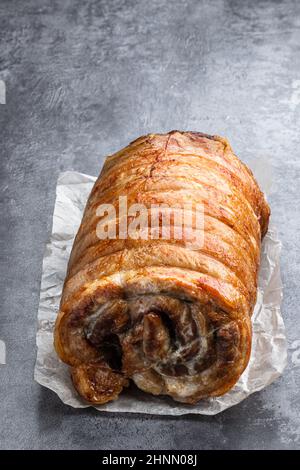 Gebratenes Schweinefleisch Rolle mit Kräutern und Gewürzen auf grauem Stein Hintergrund Stockfoto