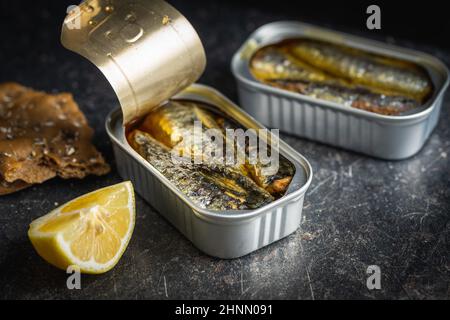 Sardinen aus der Dose. Seefisch in Zinndose auf schwarzem Tisch. Stockfoto