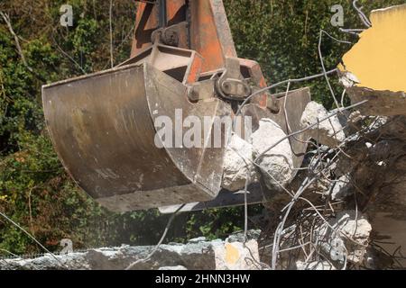 Verladung von Bauschutt mit einem Bagger in staubiger Umgebung Stockfoto