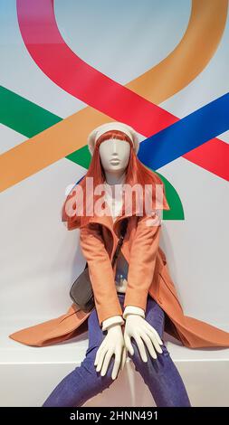 Eine Frau Schaufensterpuppe in luxuriöser Winter- oder Herbstkleidung in einem Schaufenster. Eine rothaarige weibliche Schaufensterpuppe zeigt eine lässige Sammlung von Kleidung. Braune Jacke. Stockfoto